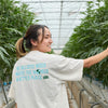 Team member in a greenhouse wearing 'We Believe' Tshirt